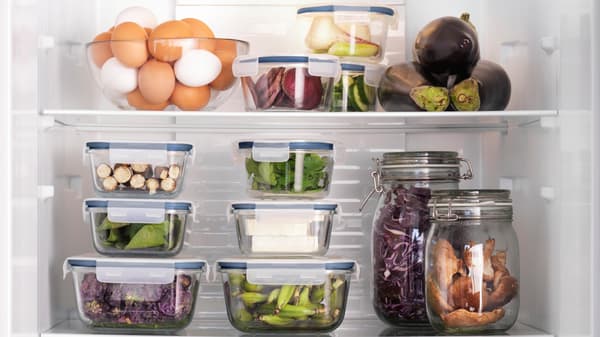 A open fridge with a lot of transparent containers with various food in them.