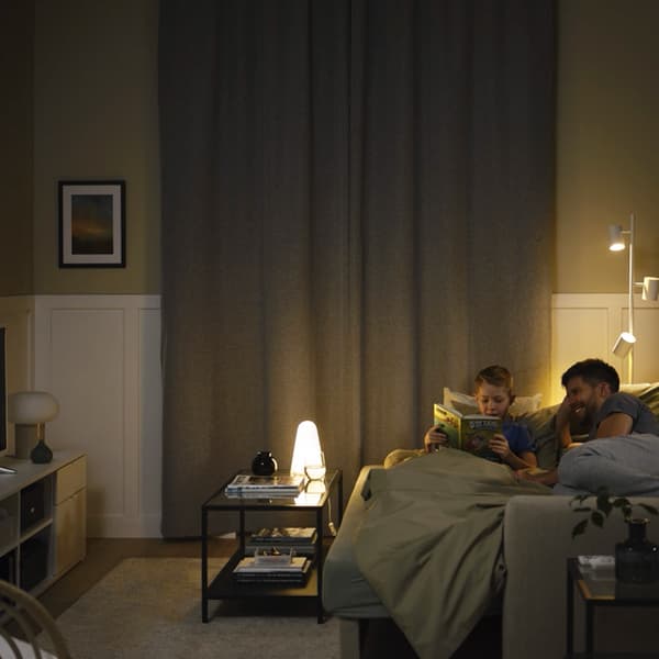 A pair of grey ROSENMANDEL block-out curtains in bedroom hanging from black BEKFRAFTA curtain rod