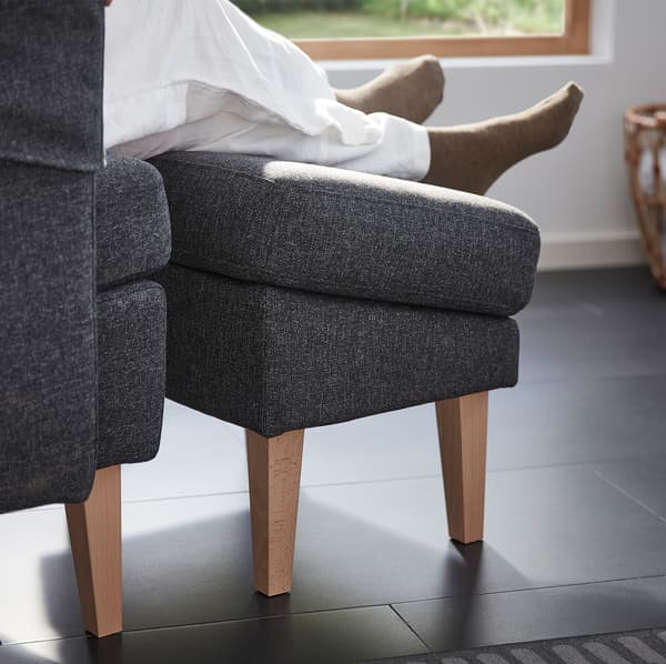 A pair of legs and feet resting on the OMTÄNKSAM footstool. Thanks to its angle it doesn’t disrupt blood circulation.
