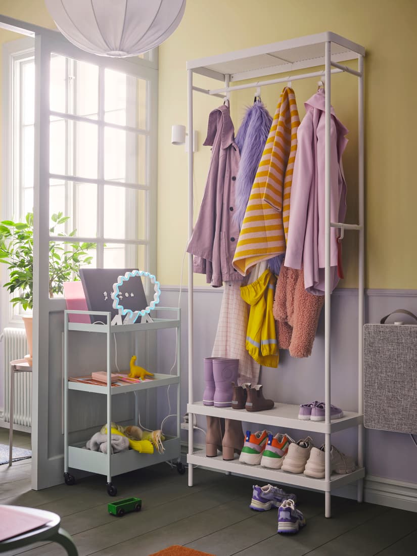 A pale green NISSAFORS trolley by a white MACKAPÄR coat rack with shoe storage in a bright hallway holding coats and shoes.