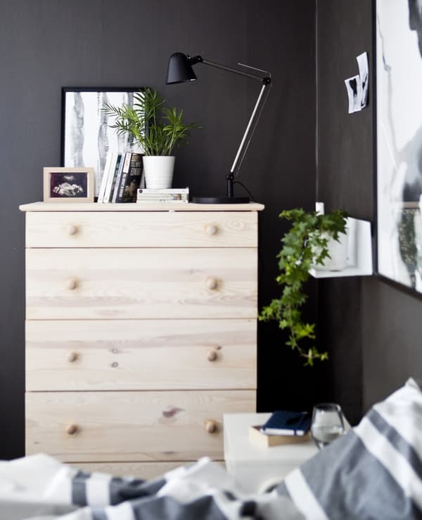 A pale-wood chest of drawers in a dark grey bedroom.