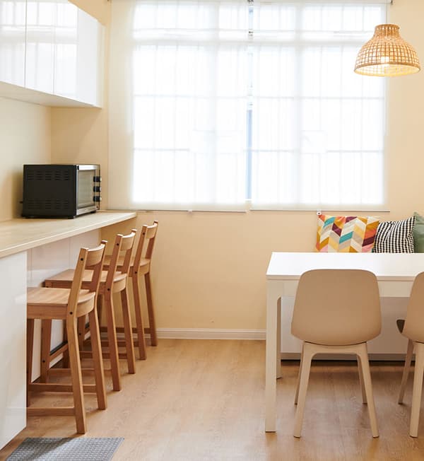 A pantry area featuring a countertop with high-chairs tucked in. 