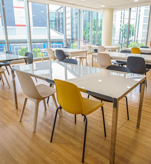 A pantry area featuring white tables and chairs of various colours.