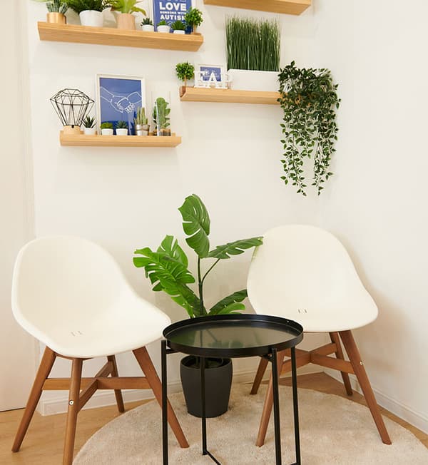 A pantry corner featuring two white chairs and a small black side table placed in front. 