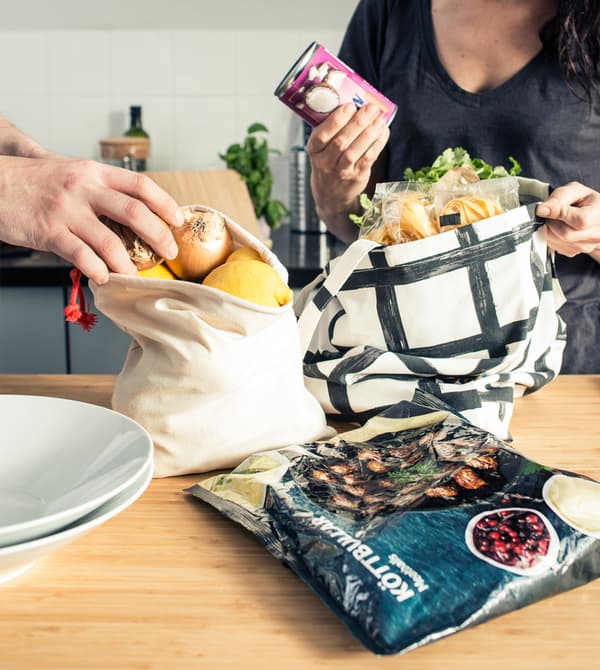 A parent and a teen unpacking bags of groceries.