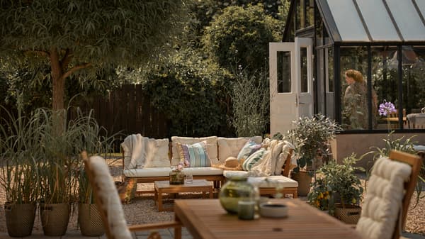 A patio with a light brown outdoor modular sofa with beige cushions, plus a light brown outdoor table with reclining chairs.