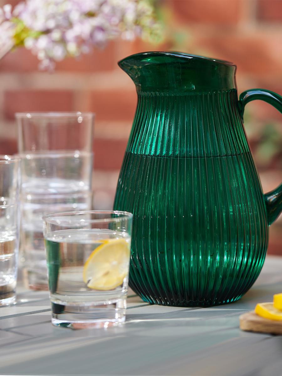 A patterned green SALLSKAPLIG jug is placed nearby clear glasses on the dining table.