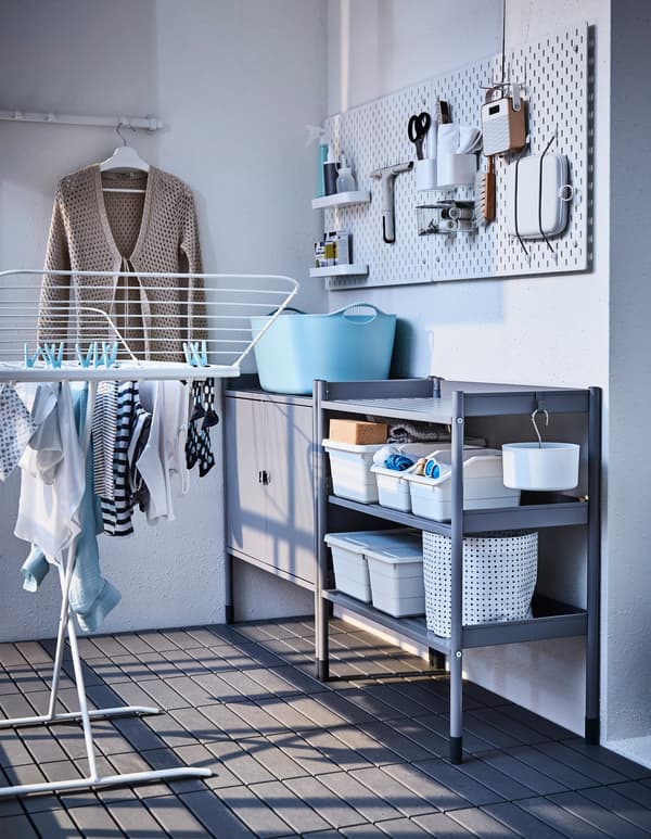 A pegboard, storage unit and wall hooks create a laundry area on a terrace.