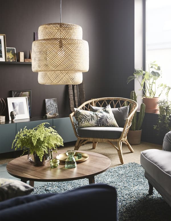 A pendant lamp made of natural woven fibres hangs above a round coffee table in a modern styled living room.