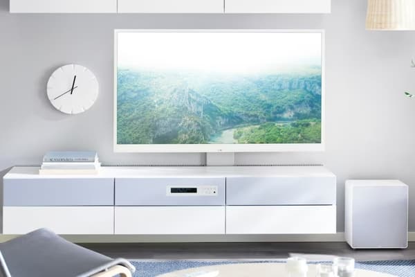A person clicks on a white remote control to control their smart TV.