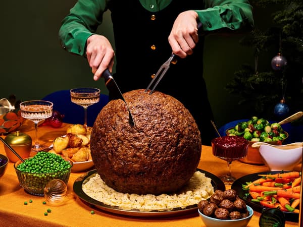 A person cutting huge turkey-sized meatball