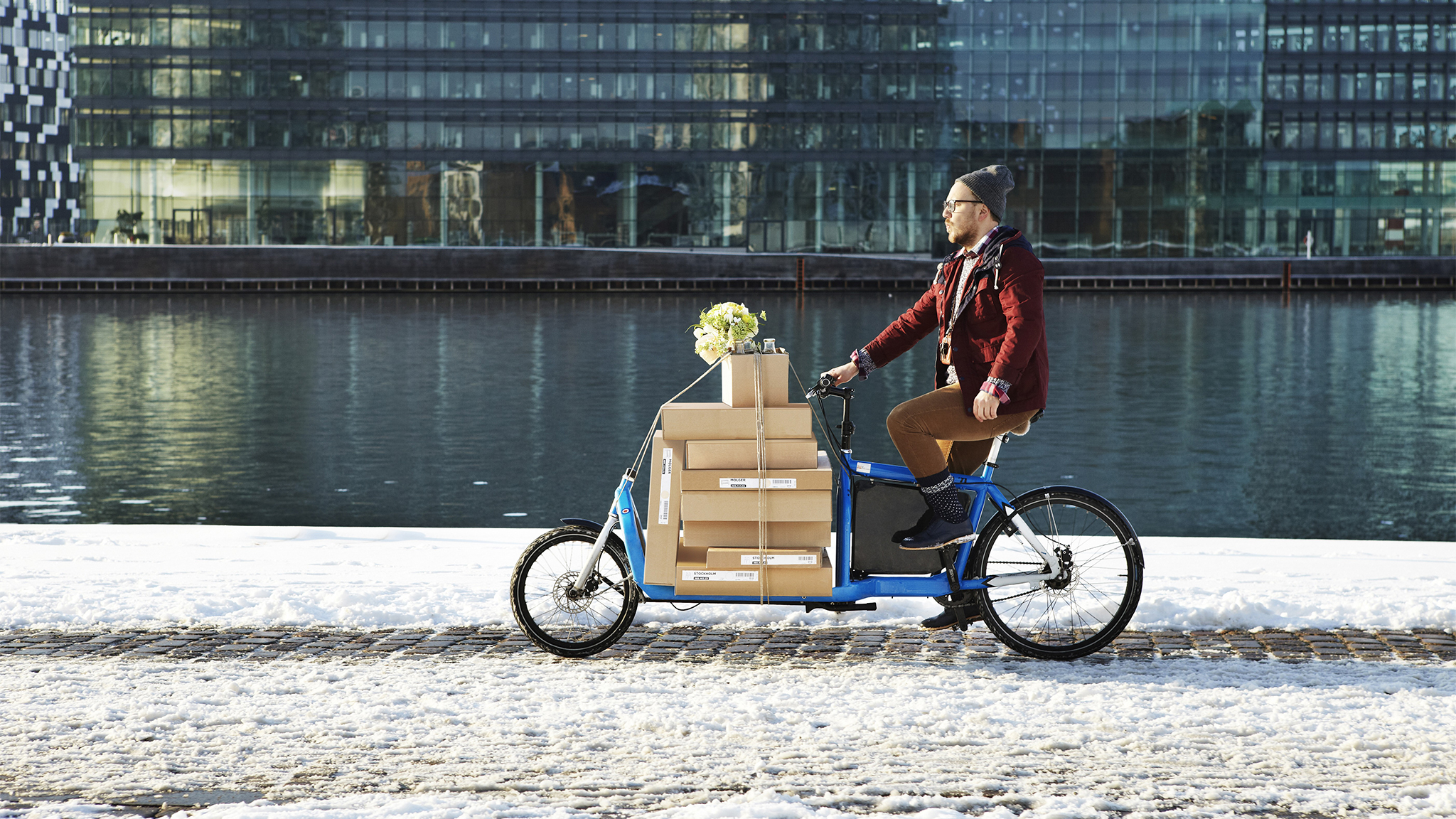 A person delivering IKEA parcels on a bicycle by the river