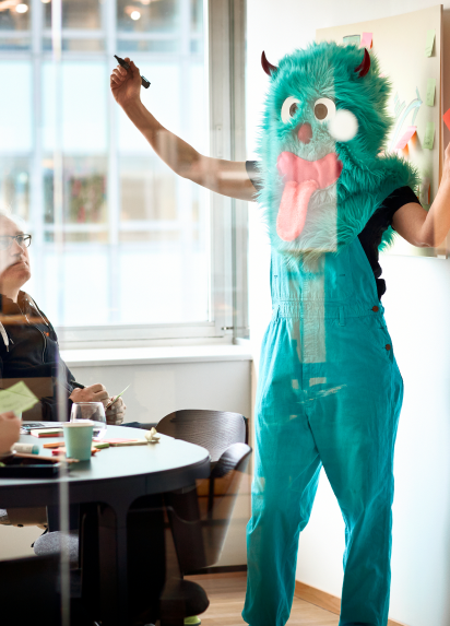 A person dressed up as a green monster with horns and its tongue out