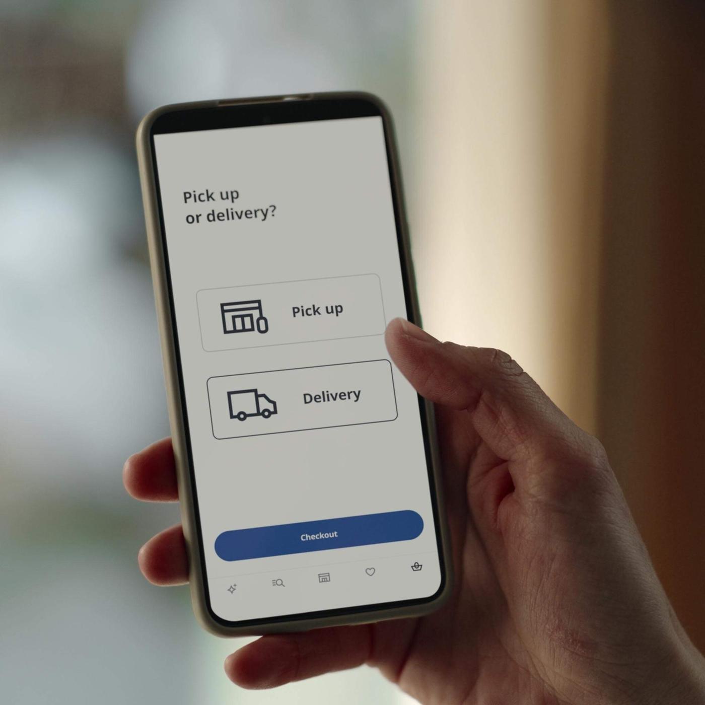 A person holding a phone and selecting the pick-up or delivery option on the IKEA app.