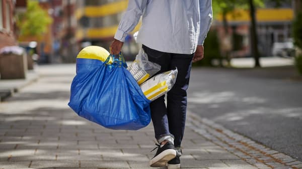 A person holding an IKEA blue bag with products in it.