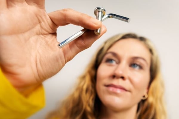 A person holding spare parts, a bolt and an allen key.