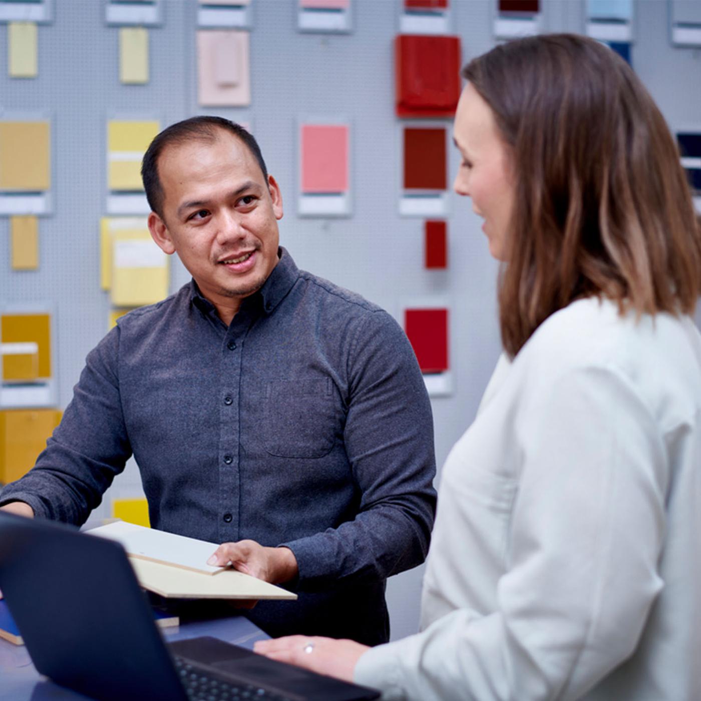 A person holding tiles discussing with another person.