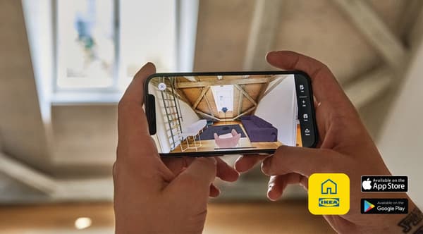 A person holds up a mobile phone and uses the KREATIV app while standing in a room planning solutions.