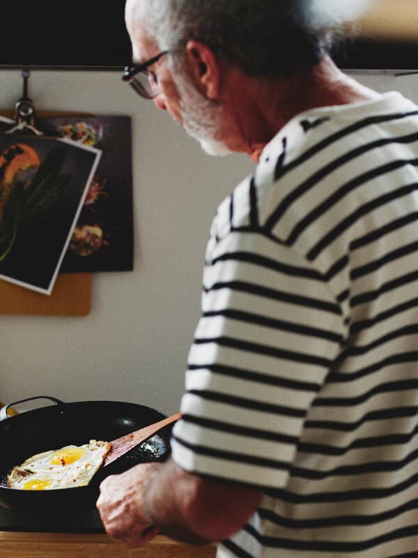 A person in a kitchen frying an egg in a carbon steel VARDAGEN frying pan.