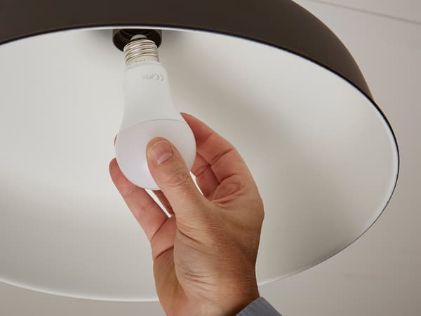 A person installing an LED bulb into a ceiling lamp.