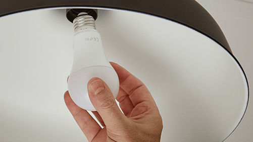 A person installing an LED bulb into a ceiling lamp.