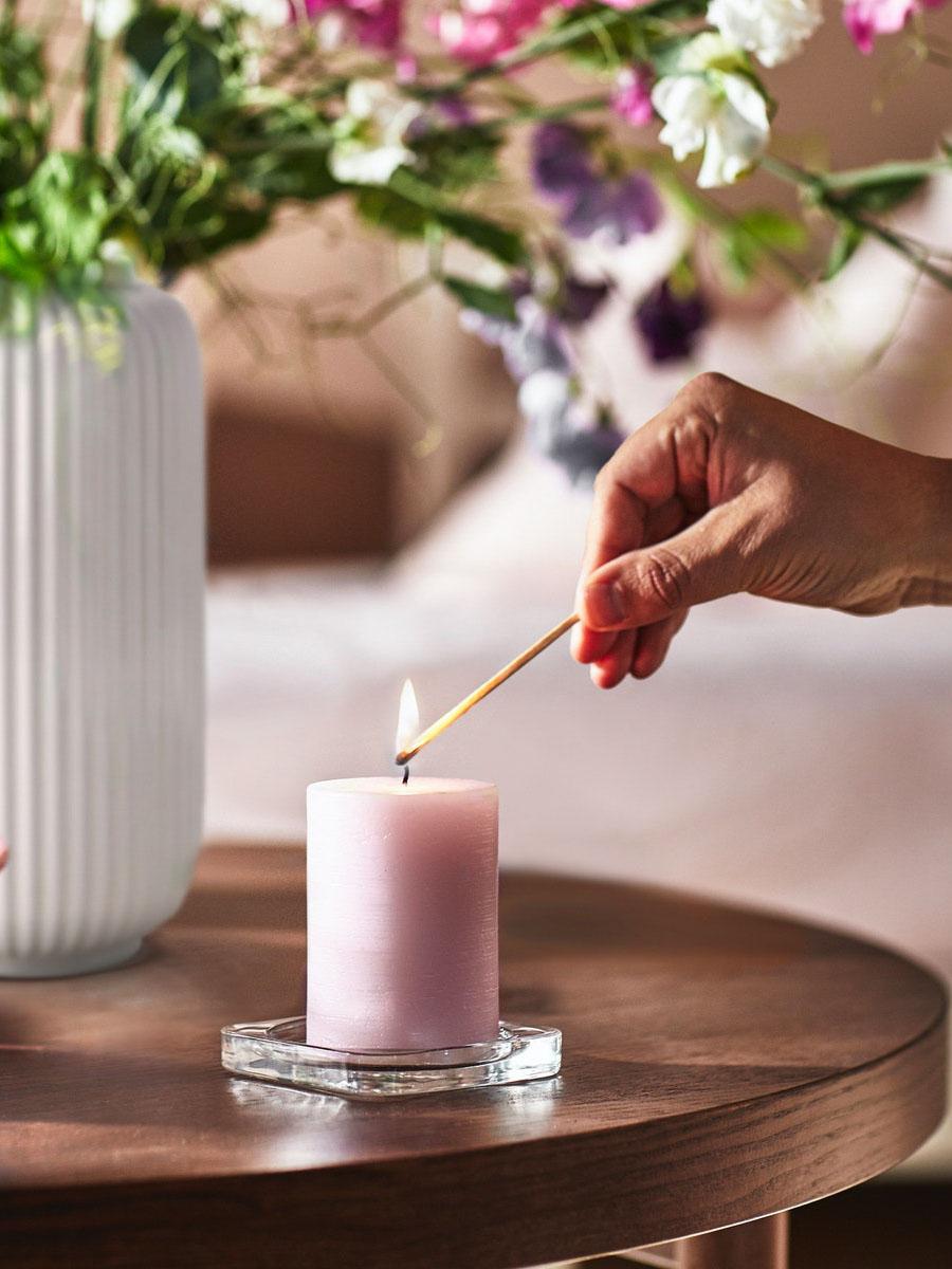 A person lighting JÄMNMOD scented candle.