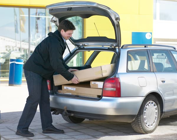 A person loading purchased items into the trunk of a car