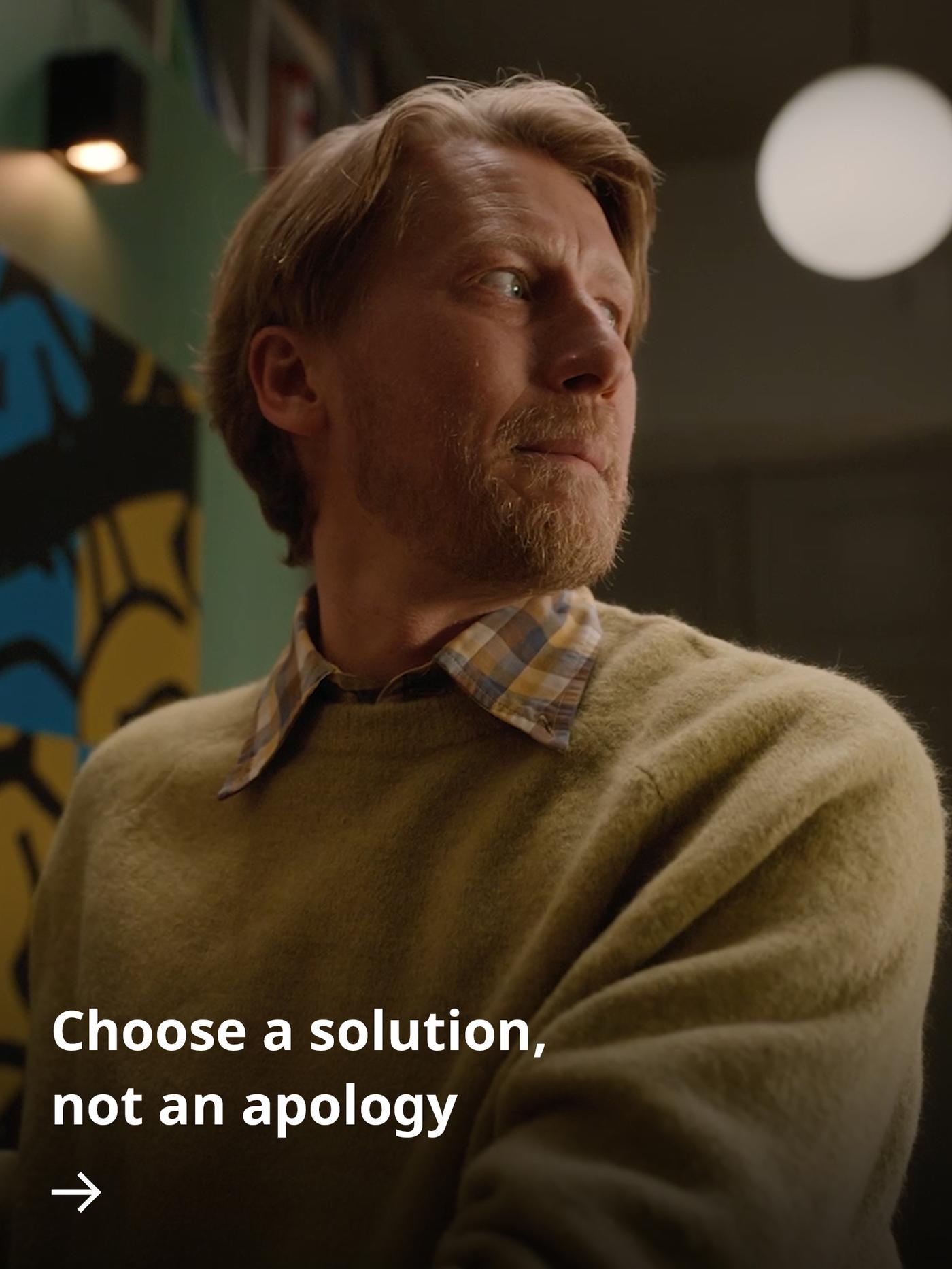 A person looks towards someone with an apologetic expression, appearing uncomfortable and slightly guilty about the state of their home.