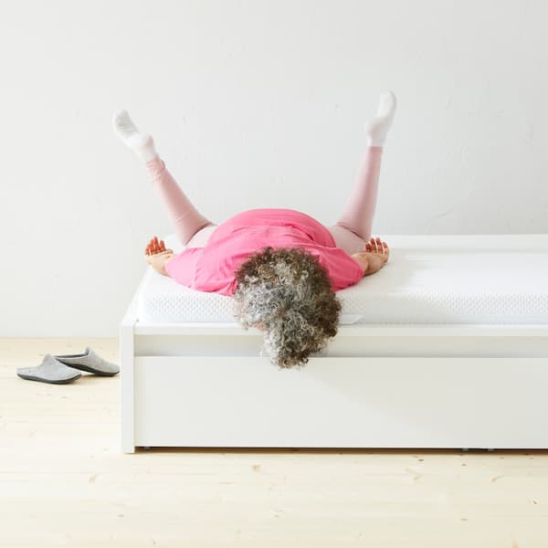 a person lying face down on a mattress with their legs in the air