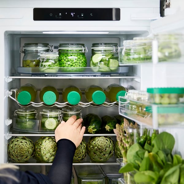 A person organising fresh produce inside a fridge using KLIPPKAKTUS clear storage boxes.