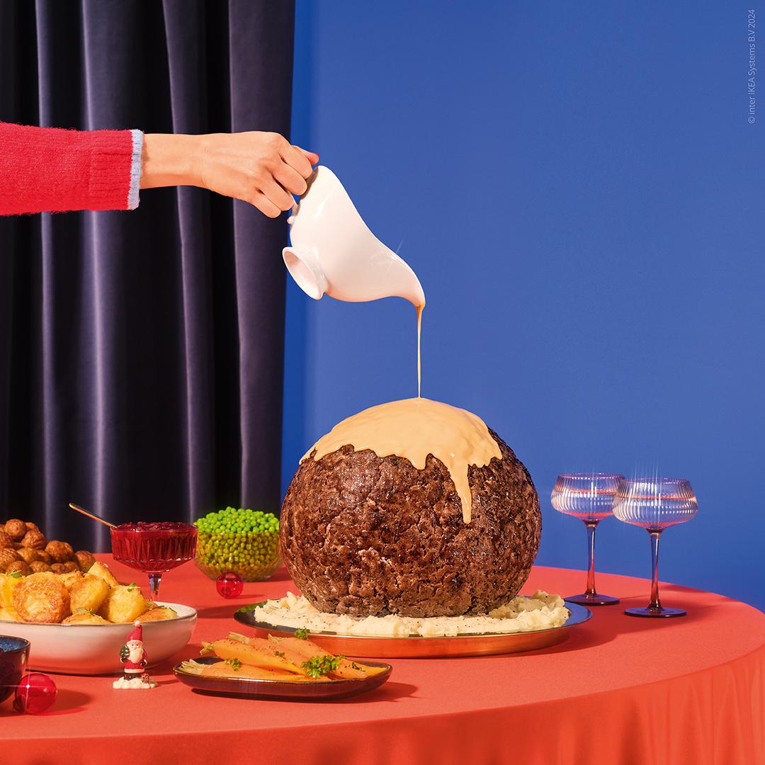 A person pouring gravy on a giant meatball