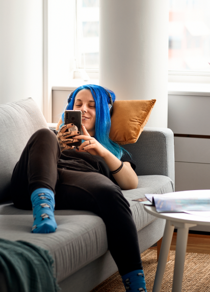 A person relaxing on a grey couch checking their phone