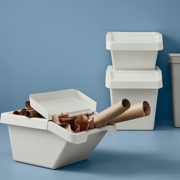 A person removing a wooden drawer from a kitchen cabinet stood up against a white wall.