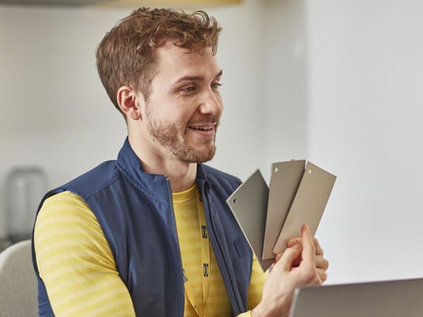 A person showing different coloured tiles in a white room.