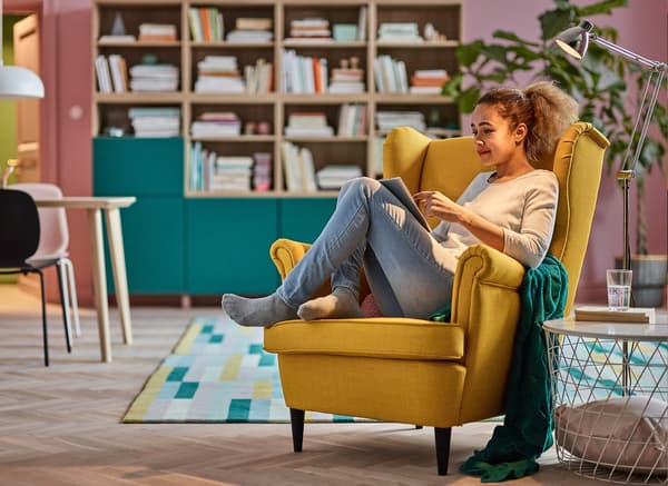 A person sitting in a yellow STRANDMON chair. 