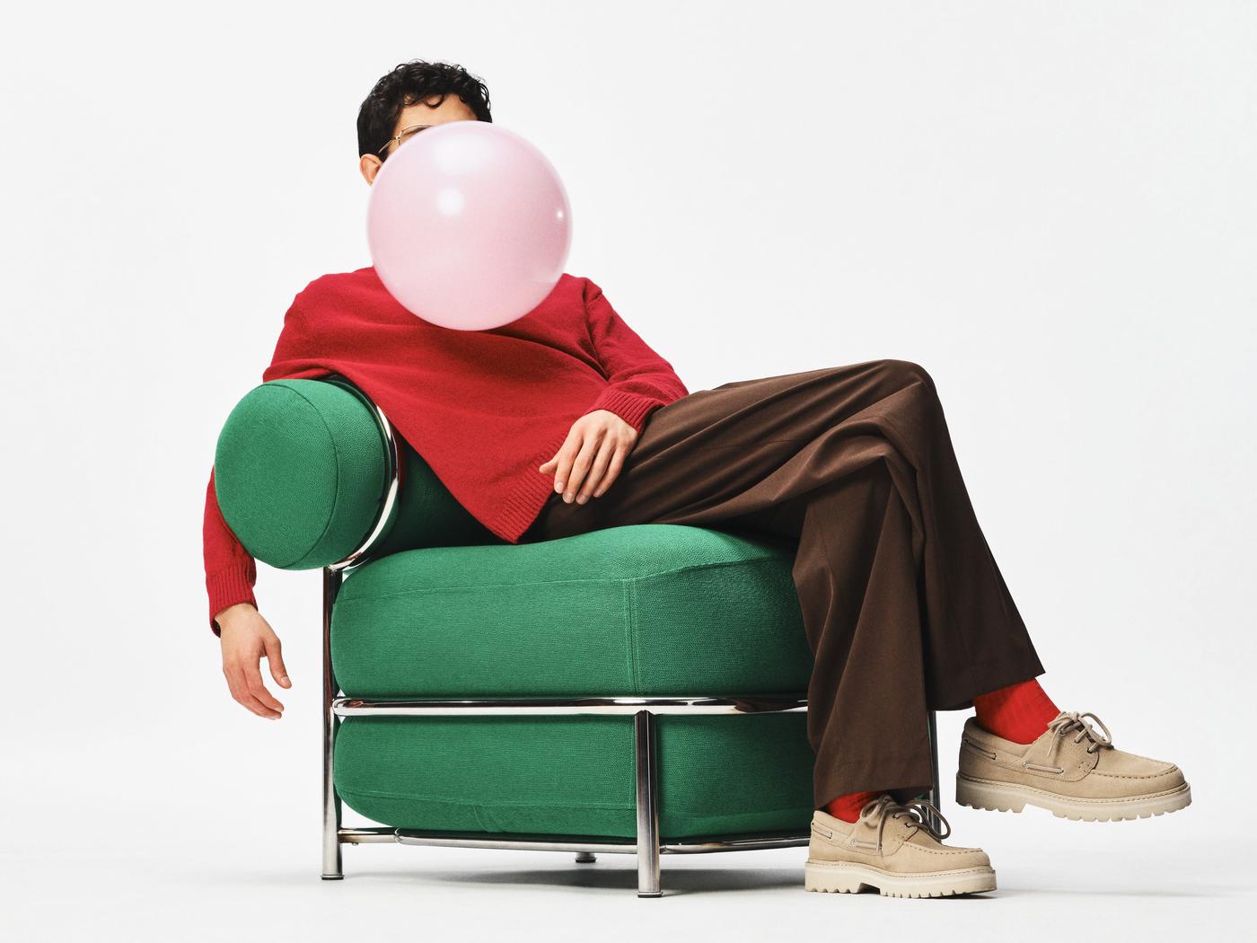 A person sitting on IKEA PS 2026 easy inflatable chair with a large pink bubble covering the persons face. 