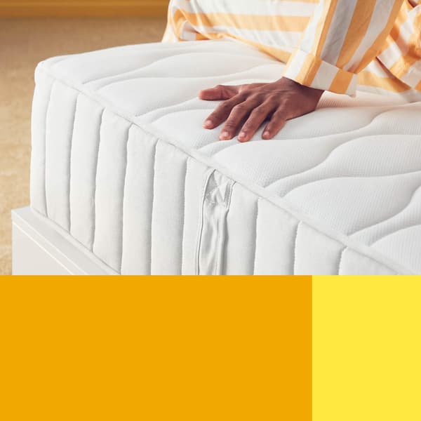 A person sitting on the edge of a mattress