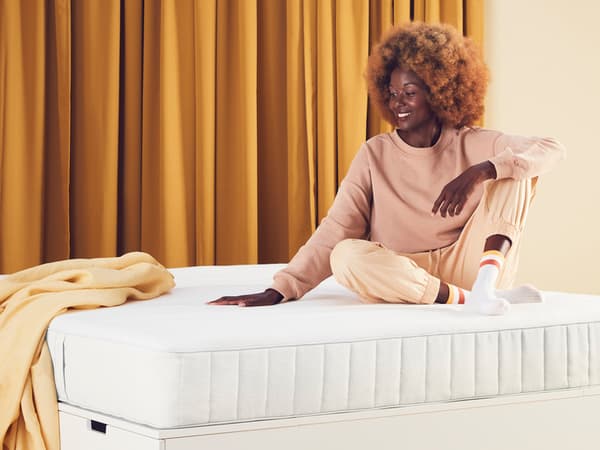 a person sitting on top of a mattress with their hand placed on top.