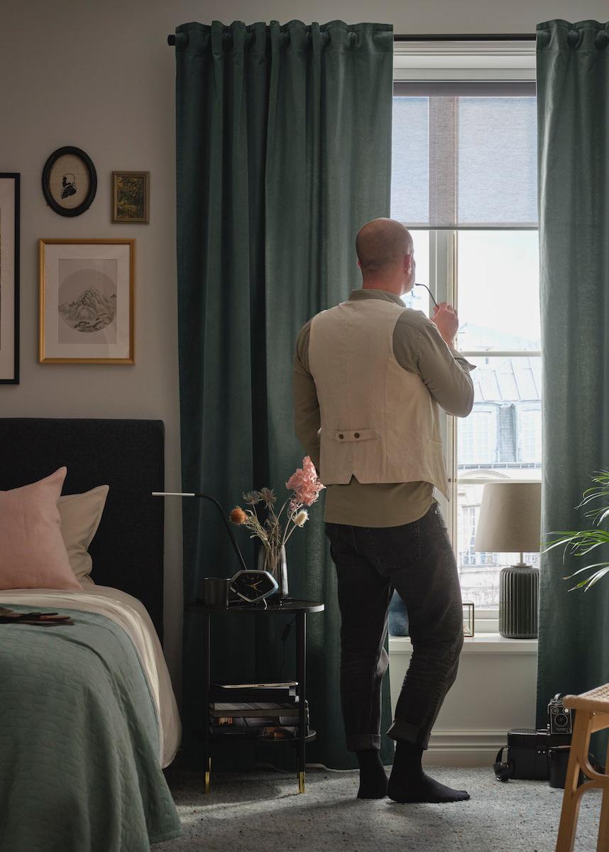 A person standing in a living room and looking at the window.