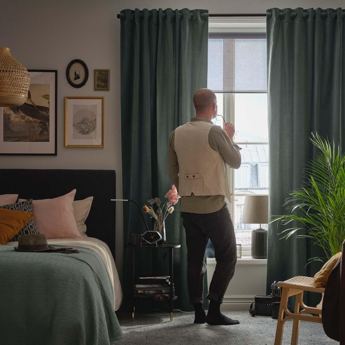 A person standing in a living room and looking at the window.