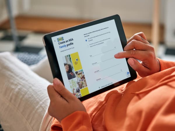 A person wearing an orange jumper using a tablet.