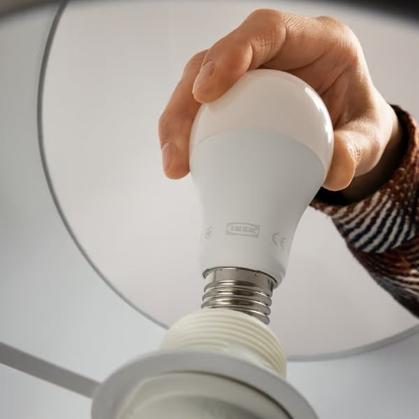 A person’s hand screwing a light bulb into a socket.