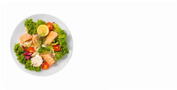 A photo of a plate with a salad with vegetables and pieces of salmon.