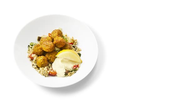 A photo of a plate with falafel with couscous, vegetables, a dollop of mayonnaise, and a slice of lemon.