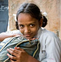 A photo portrait of a young Indian girl in a classroom