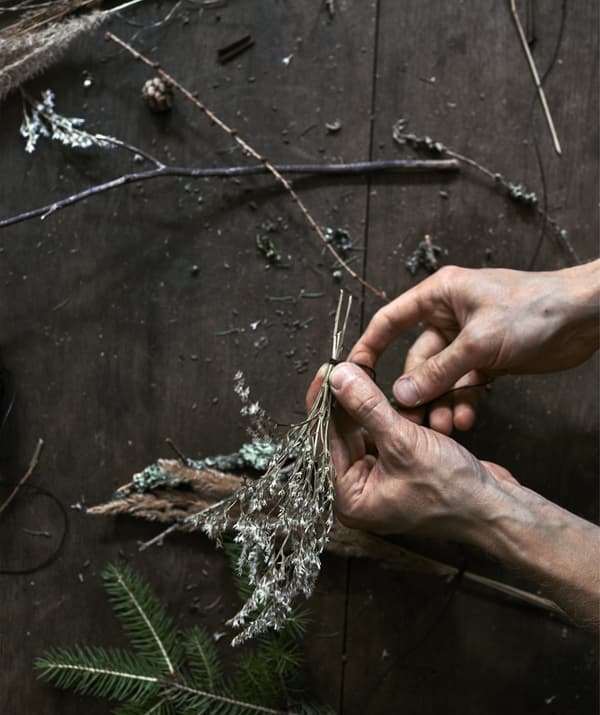 A photo shows someone tying a branch with leaves using sewing thread.