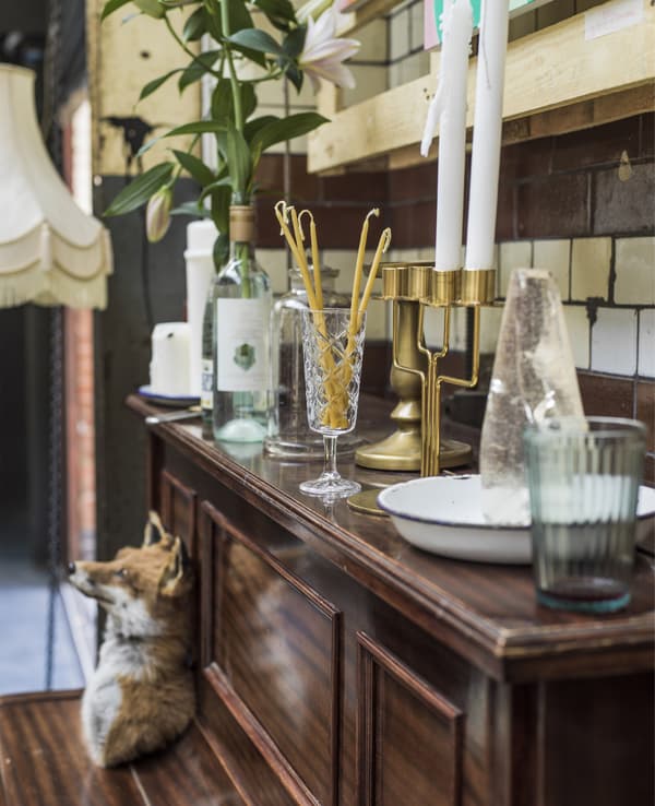A piano with candlesticks, candles and glassware.