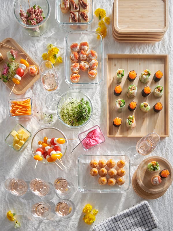 A picnic blanket filled with snacks in various IKEA 365+ food containers in glass.