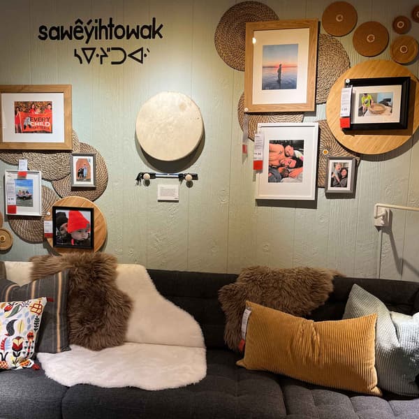 A picture collage over a sofa with cushions and throws.