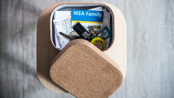 A picture taken from above of an IKEA Family card in a box placed on a blond wood stool.